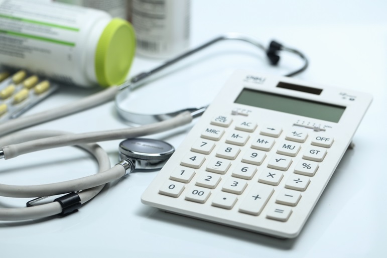 A calculator, stethoscope, and medicine bottles against a white background.